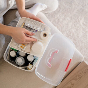 Person öffnet eine Aufbewahrungsbox mit verschiedenen Medikamenten, Fläschchen und Salben.